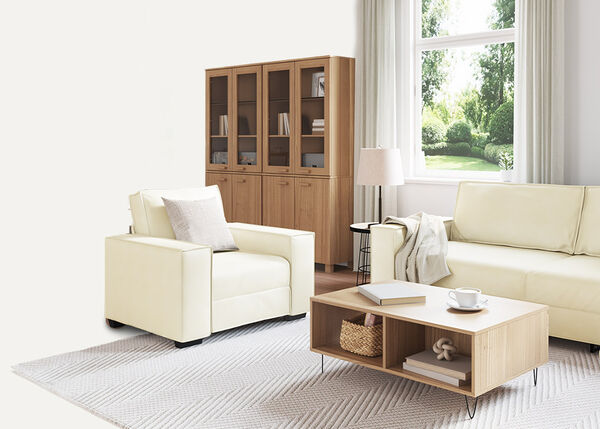 Valkoinen 2-istuttava sohva sis&auml;tiloissa tyynyill&auml; ja torkkupeitolla.