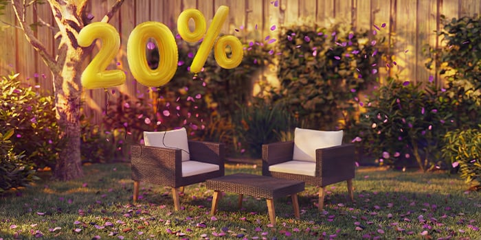 Ulkorottinkiset lounge-tuolit tyynyillä ja pienellä pöydällä puutarhaympäristössä, koristeltu vaaleanpunaisilla konfeteilla ja kultaisilla ”20 % alennus” -ilmapalloilla, korostaen kausitarjouksia puutarhan loungekalusteista.